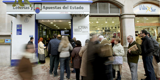 Numerosas personas hacen cola ante un c�ntrica Administraci�n de Loter�a de Valencia.